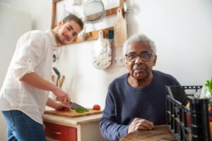 carer and old man making food